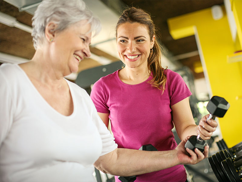 A senior woman talking with a fitness instructor